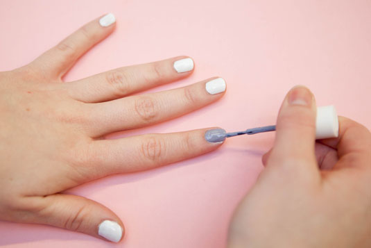 mujer pintandse las uñas de color blanco y gris