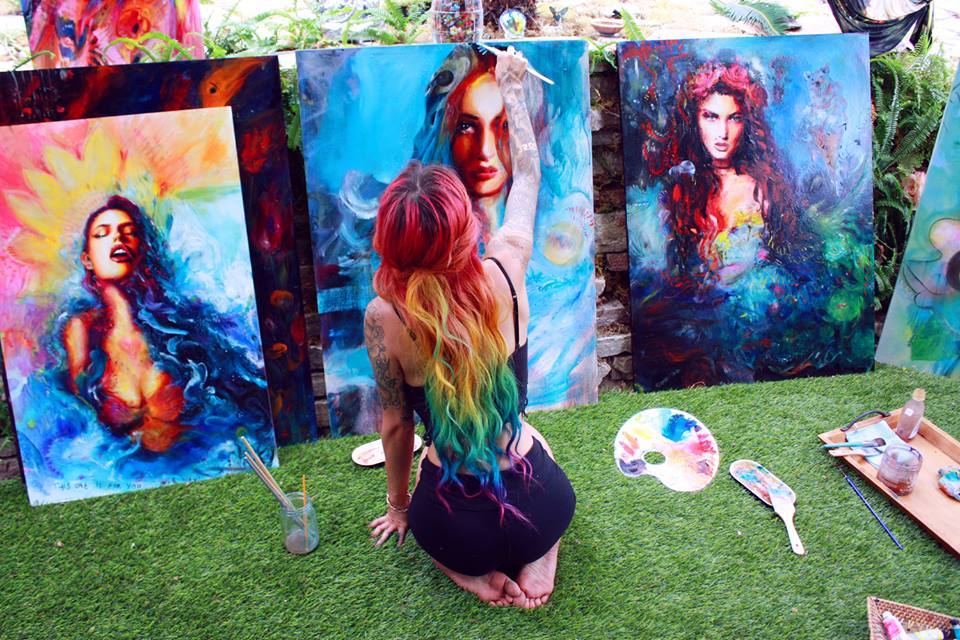 Голая длинноволосая художница рисует красками