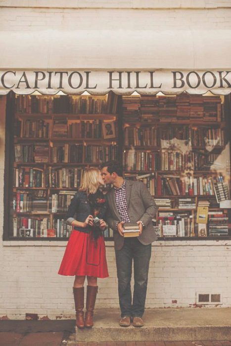 Pareja de novios besándose afuera de una tienda de libros