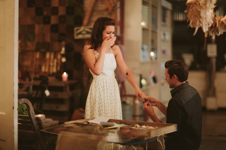 Novio sobre una rdilla pidiendole matrimonio a una chica mientras están en un restaurante 