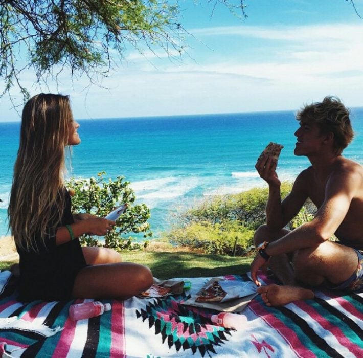 Pareja de novios sentados sobre una manta en un picnic 