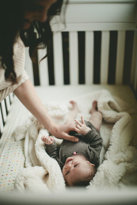 Mamá viendo a un bebé en su cuna 