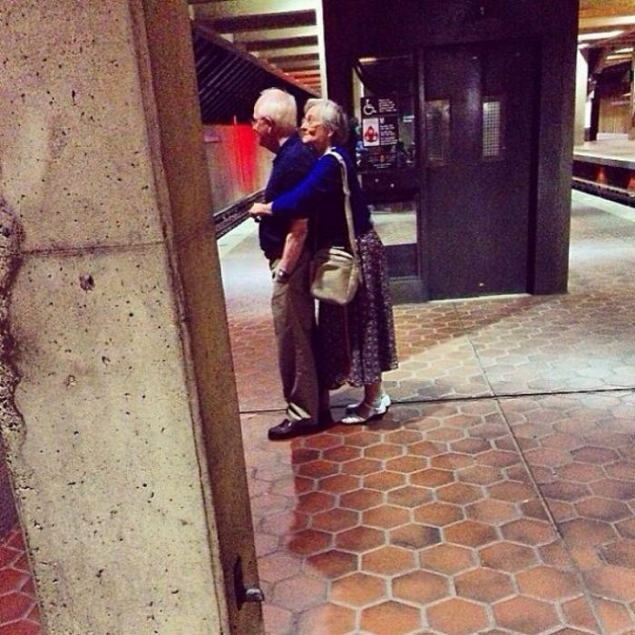 Pareja de ancianos abrazados esperando el tren 