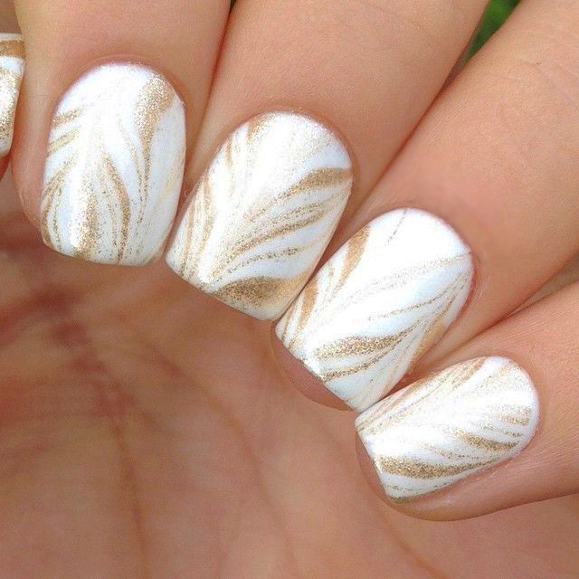 Uñas con diseños minimalistas en color blanco con líneas en color dorado