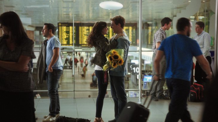 pareja en aeropuerto con ramo de flores en las manos 
