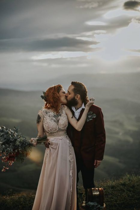 Novios celebran una boda vikinga al aire libre, esposos besándose en una montaña