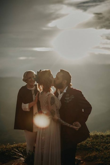 Boda vikinga en la montaña al aire libre, novio besando a novia al atardecer