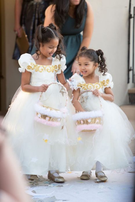 Niñas llevando cestas con flores y vestidos abultados