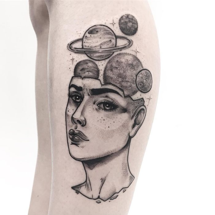 Tatuaje de la cabeza de una mujer con planetas saliendo de su craneo