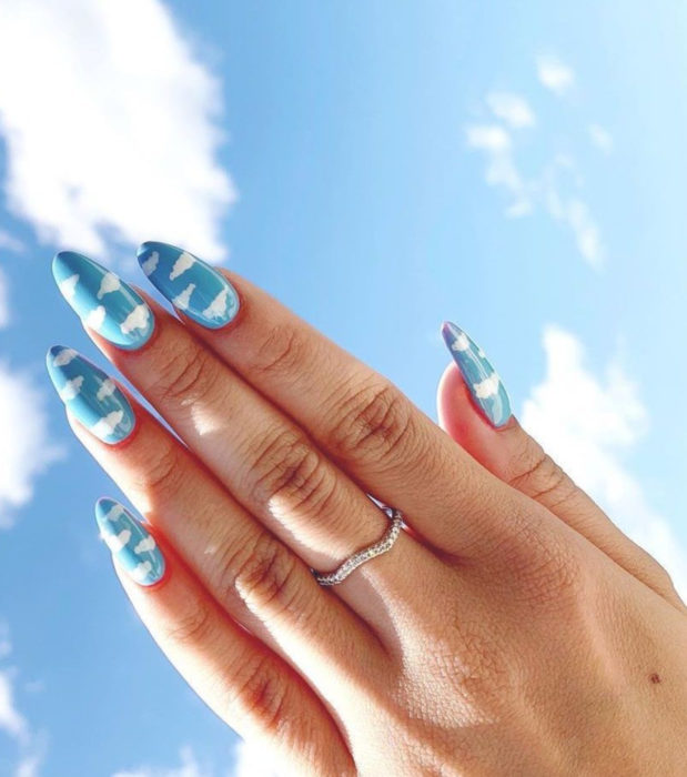 Manicura con diseño de cielo y nubes; uñas en forma de almendra pintadas con esmalte azul