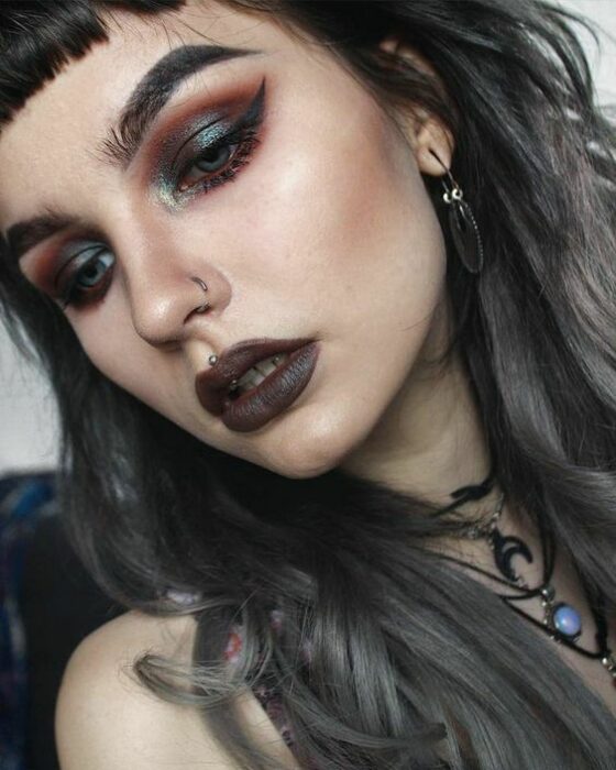 Chica de piel clara con labial gris y ojos con sombras ahumadas color verde y naranjas