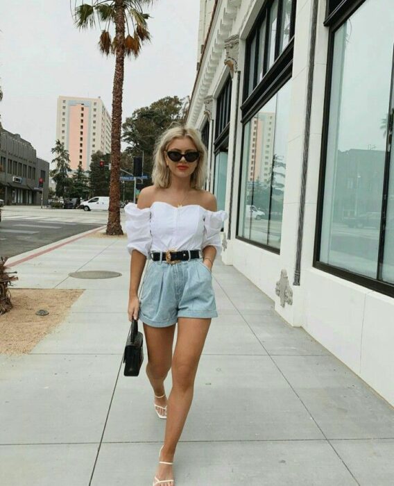 Chica usando unos mom shorts acompañados de blusa hasta los hombros y sandalias 