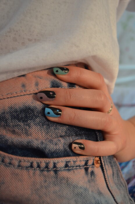 Chica mostrando sus uñas con diseño Yin Yang en color azul y café 